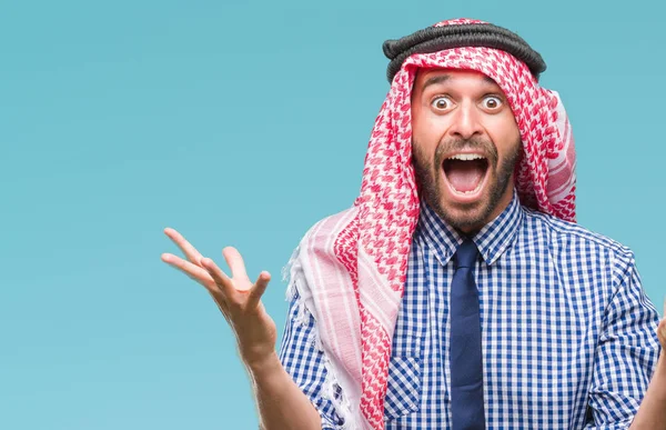 クーフィーヤを着た若いハンサムなアラビアン ビジネス男クレイジーを祝う背景を分離した腕を上げると成功のためびっくりし 叫んで興奮して目を開きます 勝者の概念 — ストック写真