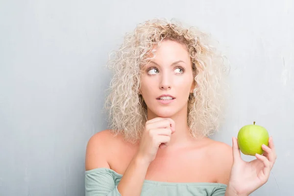 Giovane Donna Bionda Sfondo Grigio Grunge Mangiare Mela Verde Faccia — Foto Stock