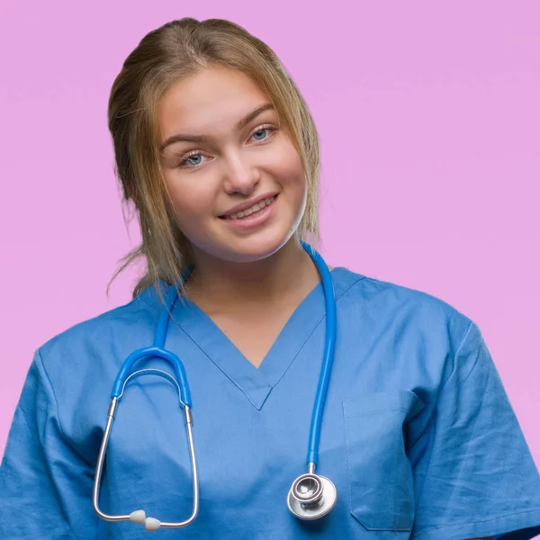 年轻的高加索医生妇女穿着外科医生制服在孤立的背景看着一边面带微笑 自然的表情 笑自信 — 图库照片