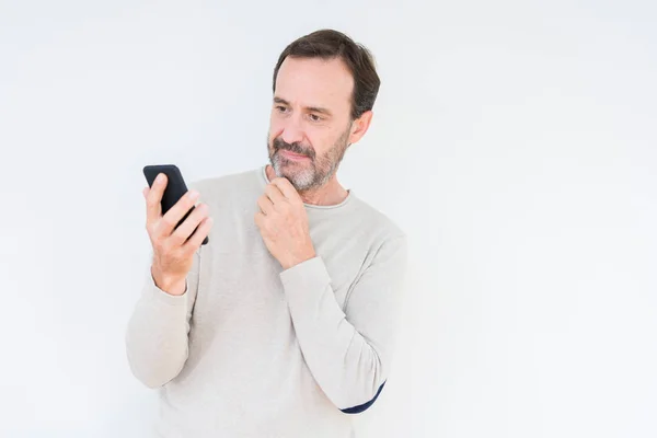 Старший Человек Используя Смартфон Изолированном Фоне Серьезное Лицо Думая Вопросе — стоковое фото