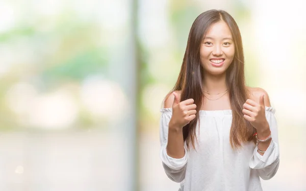 年轻的亚洲妇女在孤立的背景下成功手势用手做积极的手势 大拇指向上微笑和快乐 看着带着欢快表情的相机 胜利者的手势 — 图库照片