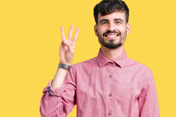 年轻英俊的男人穿着粉红色的衬衫在孤立的背景显示和手指第三 而微笑着自信和快乐 — 图库照片