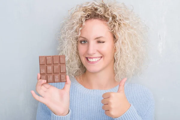 Junge Blonde Frau Über Grunge Grey Wall Eating Chocolate Bar — Stockfoto