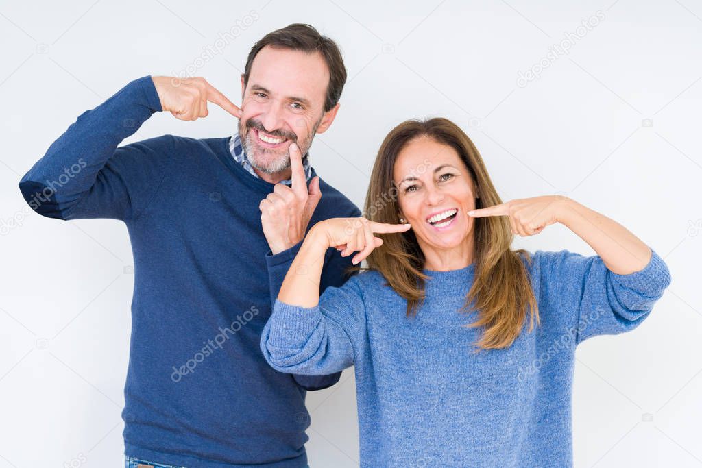 Beautiful middle age couple in love over isolated background smiling confident showing and pointing with fingers teeth and mouth. Health concept.
