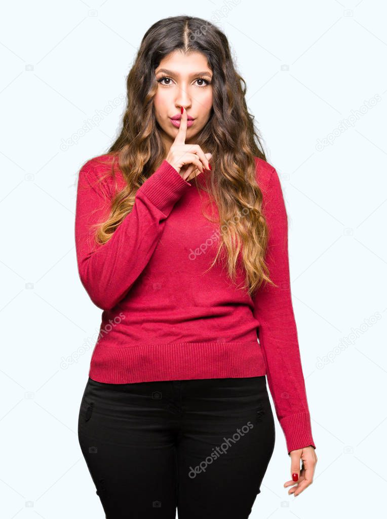 Young beautiful woman wearing red sweater asking to be quiet with finger on lips. Silence and secret concept.