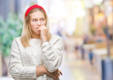 Stresli ve gergin elle çivi ısırma ağzına bakarak izole arka plan üzerinde kış kazak giyen genç beyaz kadın. Anksiyete sorunu.