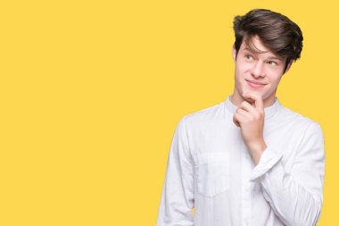 Genç yakışıklı iş adamı çene düşünme hakkında soru, dalgın ifade üzerine el ile izole arka plan üzerinde. Düşünceli yüzüyle gülümsüyor. Şüphe kavramı.