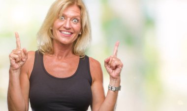 Orta yaş sarışın kadın izole arka plan üzerinden hayran ve yukarıya bakıp parmakları ile işaret şaşırttı ve silah kaldırdı.