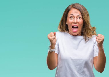İzole arka plan kutlama üzerinde orta yaş İspanyol kadın kıdemli şaşırttı ve başarı için kaldırdı kollarını açarak hayret ve gözleri açık. Kazanan kavramı.
