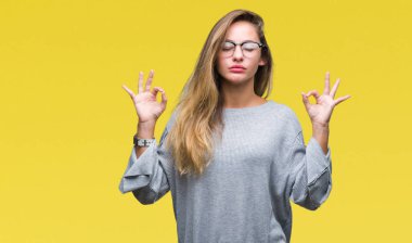 Genç güzel sarışın kadın gözlük izole arka plan üzerinde dinlenmek ve gülümseyen gözlerle kapalı parmak jestle meditasyon yapıyor. Yoga kavramı.