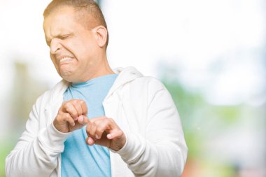 İzole arka plan üzerinde sweatshirt giyen orta yaş Arap adam tiksinti ifadesi, memnun ve korkulu tiksinti yüz yapıyorsun çünkü nefret tepki. Elleriyle kaldırdı. Sinir bozucu kavramı.