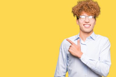 Genç yakışıklı iş adamı ile neşeli bir gülümseme ile el ve parmak kadar yan yüzünde mutlu ve doğal ifade ile işaret yüz ile gözlüklü afro