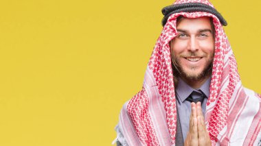 Uzun saçlı keffiyeh ellerle birlikte AF emin gülümseyen için soran dua izole arka plan üzerinde giyen genç Arap yakışıklı.