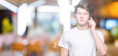 Smartphone akıllı yüzünde ciddi düşünme emin bir ifade ile izole arka plan üzerinde konuşan genç adam