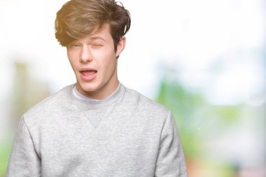 Seksi bir ifadeyle, neşeli ve mutlu yüzünü kameraya bakarak göz kırpıyor izole arka plan üzerinde sweatshirt giyen genç yakışıklı sportif adam.