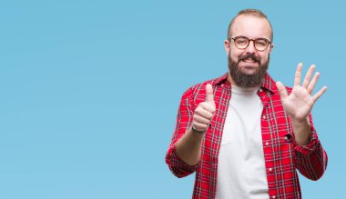 Gösterilen arka plan üzerinde gözlük takan Genç beyaz hipster adam izole ve parmakları ile işaret kendinden emin ve mutlu gülümseyerek süre 6 numara.