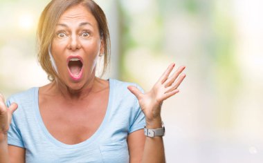 Orta yaş üst düzey İspanyol kadın deli kutluyor arka plan izole ve başarı için kaldırdı kollarını açarak hayrete ve heyecanlı çığlık gözleri açık. Kazanan kavramı