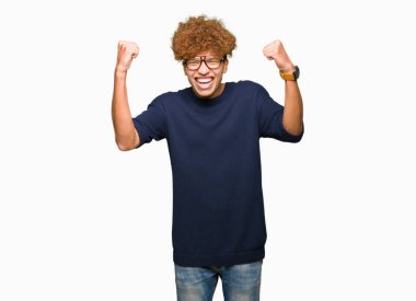 Yakışıklı delikanlı ile gülümseyen ve başarı için çığlık çok mutlu ve heyecanlı kaldırdı, silah ile kazanan jest yapıyor gözlüklü afro. Kutlama kavramı.