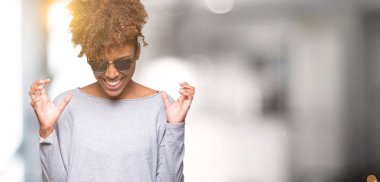 Güzel genç Afro-Amerikan kadın üzerinde güneş gözlüğü takıyor arka plan deli izole ve deli bağırarak ve agresif ifade ve silah kaldırdı bağırıyor. Hayal kırıklığı kavramı.