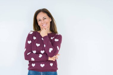 Emin çapraz kollar ve çeneme kaldırdı el ile gülümseme ile kameraya bakarak izole arka plan üzerinde kalp kazak giyen güzel orta yaş kadın. Pozitif düşünce.