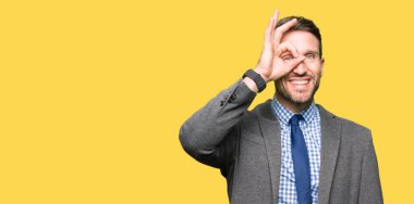 Yakışıklı iş adamı giyen takım elbise ve gülümseyen, parmakları ile mutlu yüz üzerinden seyir göz el ile ok jest yapıyor kravat.