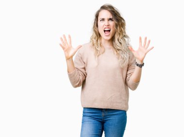 Sweatershirt üzerinde giyen genç güzel sarışın kadın arka plan deli izole ve deli bağırarak ve agresif ifade ve silah kaldırdı bağırıyor. Hayal kırıklığı kavramı.