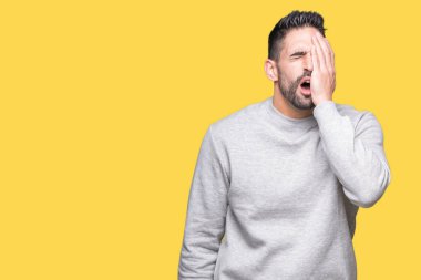 Yarım yüz, göz ve ağız el ile kapsayan yorgun esneme izole arka plan üzerinde sweatshirt giyen genç yakışıklı adam. Acı yüzü acıyor.