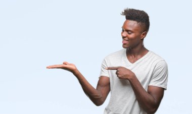 Genç Afro-Amerikan adam üzerinden hayran ve el ile sunulması ve parmak ile işaret ederken kameraya gülümseyen izole arka plan.