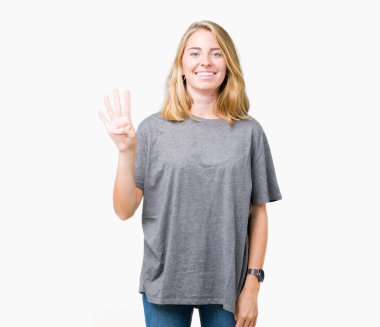 Gösterilen ve parmakları ile işaret izole arka plan üzerinde büyük boy rahat t-shirt giyen güzel genç kadın kendinden emin ve mutlu gülümseyerek süre dört numara.