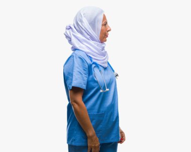 Orta yaş üst düzey Arap hemşire kadın giyiyor hijab izole arka tarafına, seyir üzerinde dinlenmek doğal yüz emin gülümseme ile pozuyla profili.