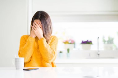 Genç güzel kadın ağlayarak süre elleriyle yüzünü kapsayan üzgün ifade ile evde kahve içme. Depresyon kavramı.