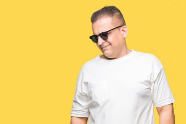 Orta yaş Arap adam wearig beyaz t-shirt ve güneş gözlüğü izole arka plan uzak tarafına gülümseme ile yüzünde, doğal ifade inceliyorlar. Kendine güvenen gülüyor.
