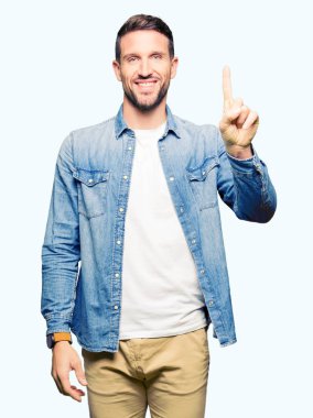 Yakışıklı adam mavi gözleri ve denim ceket gösterme ve kendinden emin ve mutlu gülümseyen bir parmak ile işaret eden oktan yukarı giyen sakal.