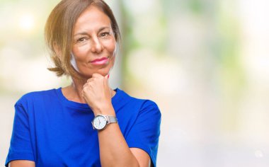 Orta yaş İspanyol kadın kıdemli emin çapraz kollar ve çeneme kaldırdı el ile gülümseme ile kameraya bakarak izole arka plan üzerinde. Pozitif düşünce.