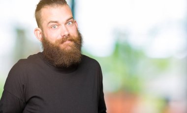Genç Sarışın giyen rahat t-shirt clueless ve şaşkın bir ifadeyle kollar ve eller kaldırdı adam. Şüphe kavramı.