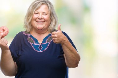 Üst düzey plus kafkas kadın yeme şeker çörek izole arka plan üzerinde mutlu ok işareti yapıyor büyük gülümseme ile boyutu, parmaklarıyla, mükemmel işaret parmak