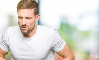 Yakışıklı adam çünkü mide üzerinde el ile rahat beyaz t-shirt giyen mide bulantısı, ağrılı hastalık hasta hissediyor. Ağrısı kavramı.
