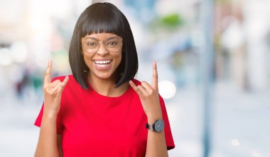 Deli ifade rock simge elle yapıyor ile bağırarak izole arka plan üzerinde gözlük güzel genç Afro-Amerikan kadın. Müzik yıldızı. Ağır kavramı.