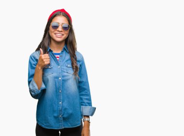 Genç güzel Arap kadın hareketi el ile mutlu yaşasın yapıyor izole arka plan üzerinde güneş gözlüğü takıyor. Kameraya bakarak başarı gösteren ile ifade onaylama.