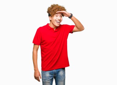 Çok mutlu ve gülümseyen uzakta el ile üzerine kafa seyir kırmızı t-shirt giyen afro saçlı Genç yakışıklı adam. Arama kavramı.