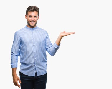 Genç yakışıklı adam neşeli sunulması ve kameraya bakarak avucunun ile işaret gülümseyen izole arka plan üzerinde.