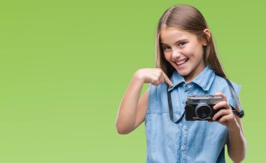 Genç güzel kız sürpriz yüz işaret parmağı kendini izole arka plan üzerinde Vintage kamera ile fotoğraf çekmek