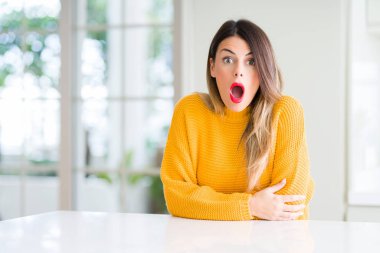 Evde korkuyor ve şok sürpriz ifade, korku ve heyecan yüz ile kış kazak giyen genç güzel kadın.