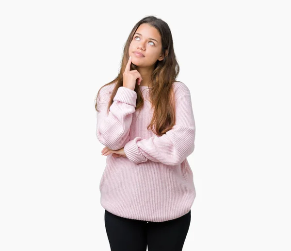 あごを考えて質問 物思いにふける式の手で隔離された背景にピンク冬のセーターを着た若い美しいブルネット女性 思いやりのある顔をして笑っています 疑いのコンセプト — ストック写真