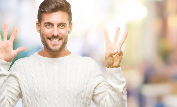 若いハンサムな男で冬のセーターを着て分離を示す背景と数 ながら自信を持って 幸せな笑みを浮かべて指で上向き — ストック写真