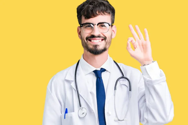 若い医者の手と指で サインをしている肯定的な笑みを浮かべて孤立の背景の上病院コートを着た男 成功した式 — ストック写真