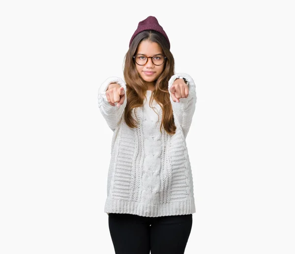 若い美しいブルネット流行に敏感な女性は 眼鏡をかけてと分離に冬帽子背景を指すと指 肯定的な陽気な笑顔でカメラ — ストック写真