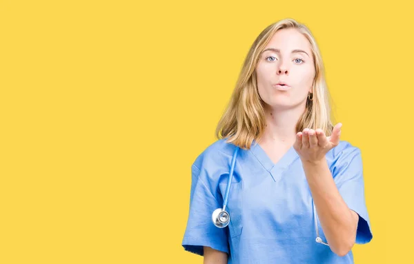 美丽的年轻医生妇女穿着医疗制服在孤立的背景看着镜头吹一个吻与手在空气中是可爱和性感的 爱的表达 — 图库照片