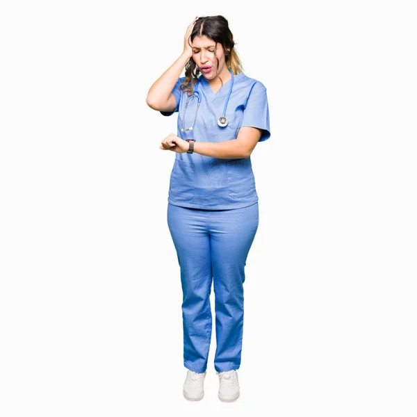 時計の時に制服を探して医療を身に着けている若い大人医師女性を心配して 遅くなってを恐れて — ストック写真