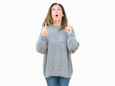 Güzel orta yaş kadın giyiyor kış kazak izole arka plan üzerinden hayran ve yukarıya bakıp parmakları ile işaret şaşırttı ve silah kaldırdı.